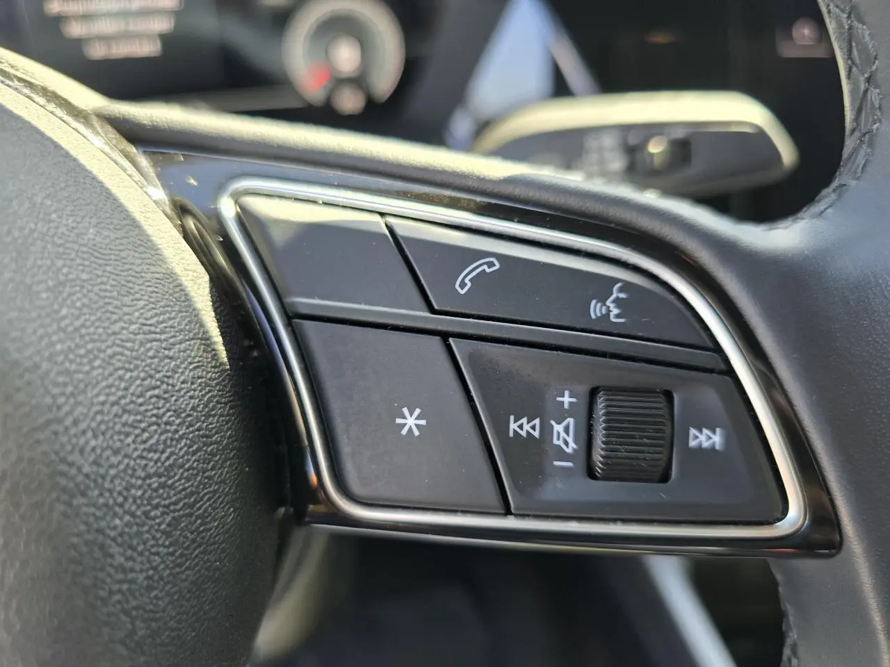 Gros plan sur les commandes multifonctions en cuir du volant côté gauche de l'Audi A3 Sportback gris argent Fleuret.