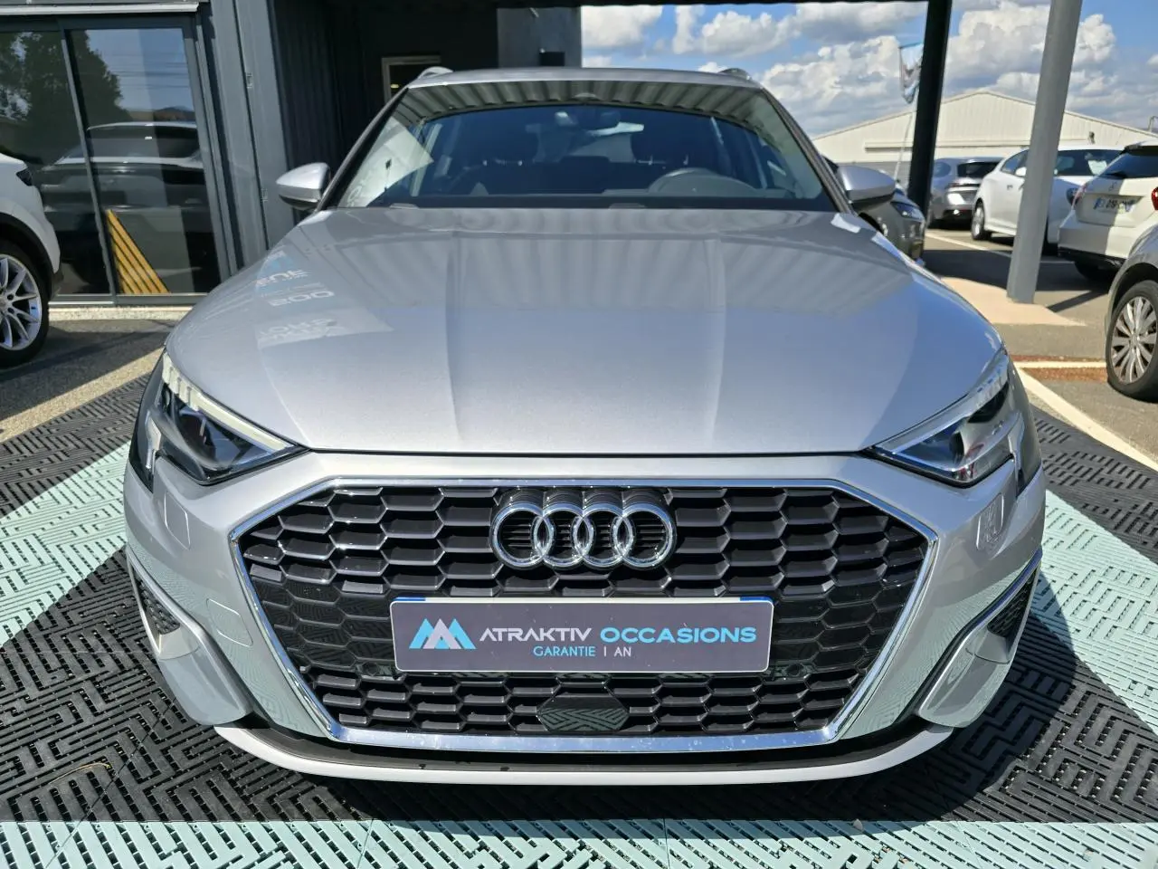 Audi A3 Sportback gris argent fleuret vue de face, mettant en valeur la calandre hexagonale et les phares LED anguleux.