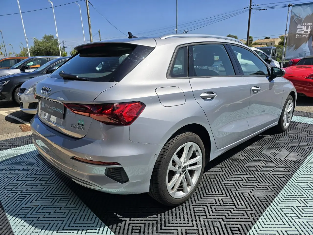 Audi A3 Sportback gris argent fleuret vue 3/4 arrière droit avec jantes alliage 17 pouces sur parking extérieur.