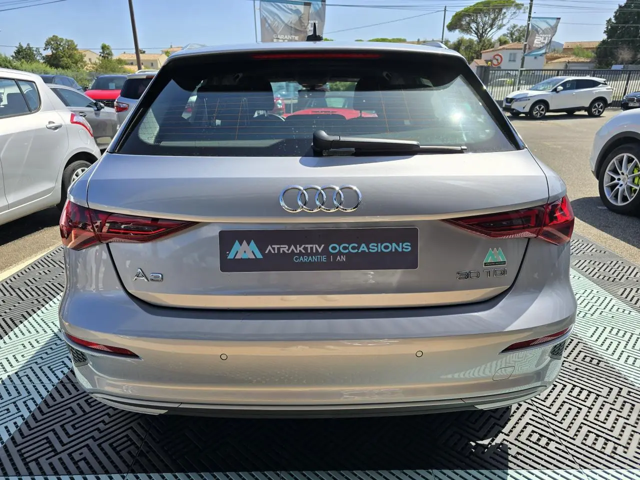 Vue arrière d'une Audi A3 Sportback gris argent fleuret avec feux LED et logo 30 TDI visible au soleil.