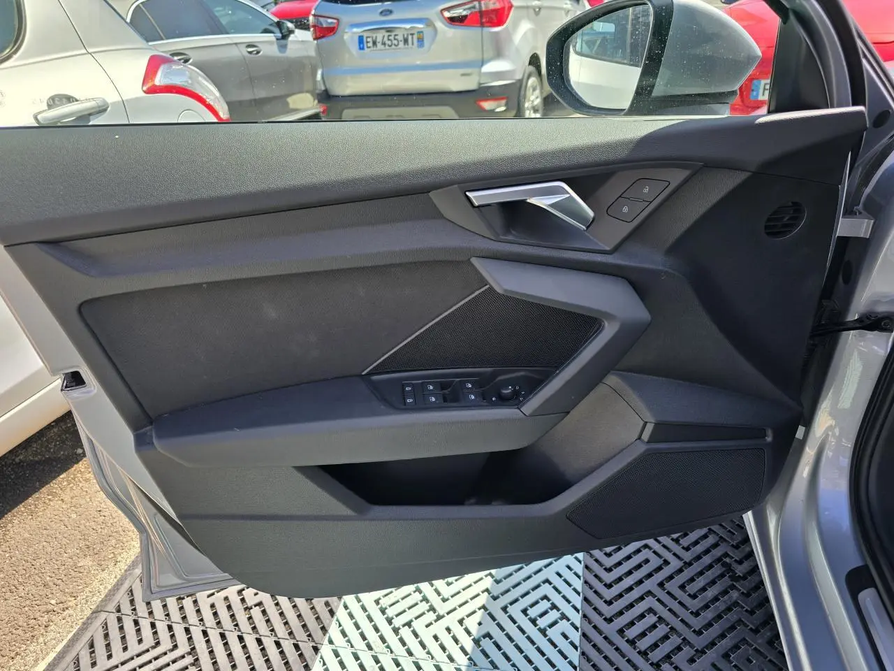 Vue intérieure côté gauche de la porte avant gris argent d'une Audi A3 Sportback 2022 avec commandes de vitres et poignée métallique.