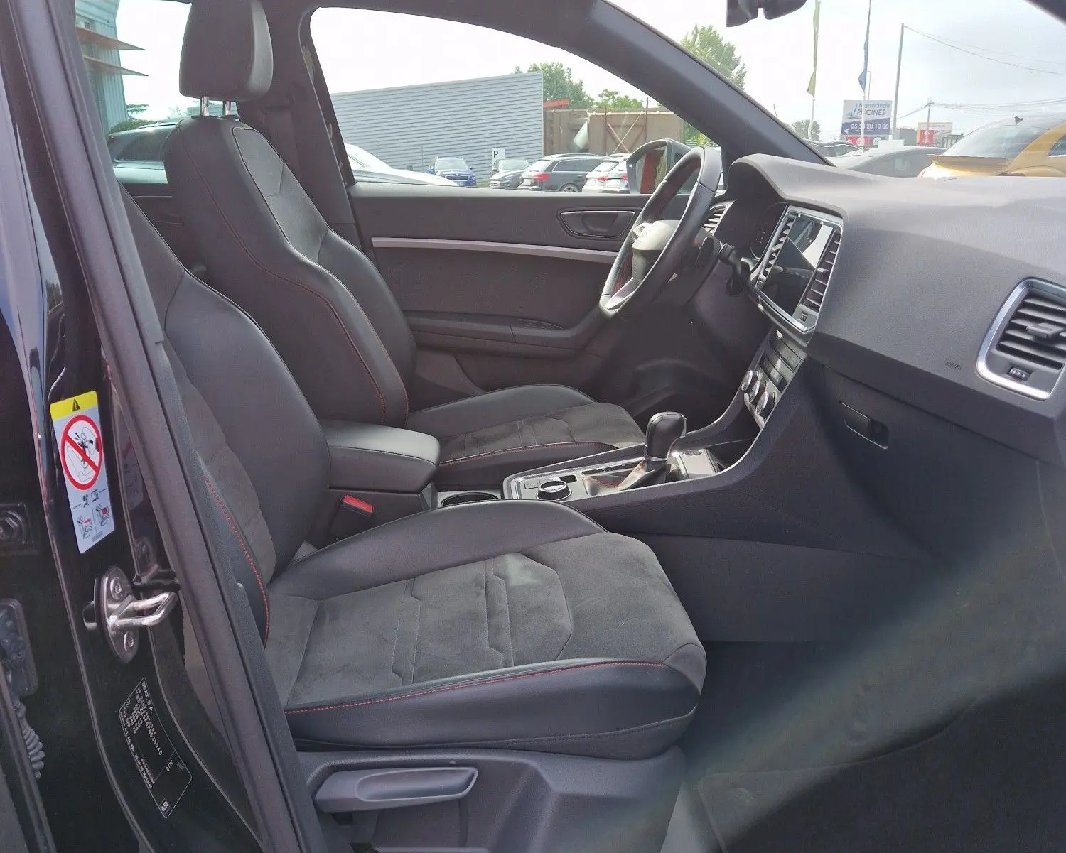 Vue intérieure côté conducteur du SEAT Ateca noir 2023, avec toit panoramique, sièges sport et tableau de bord numérique.