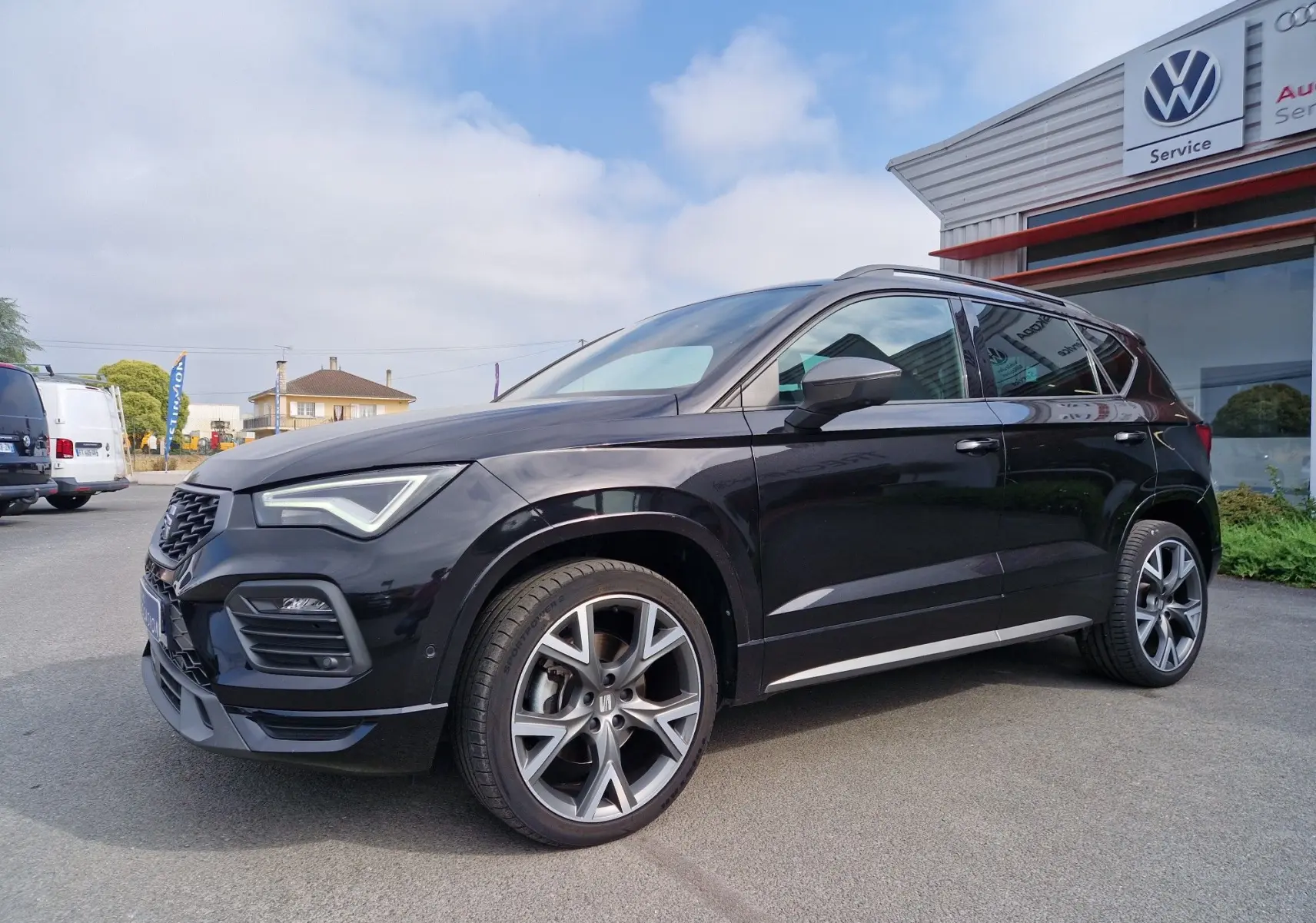 Vue 3/4 avant droite d'un SEAT Ateca noir 2023 avec jantes alu 19 pouces et toit panoramique électrique.