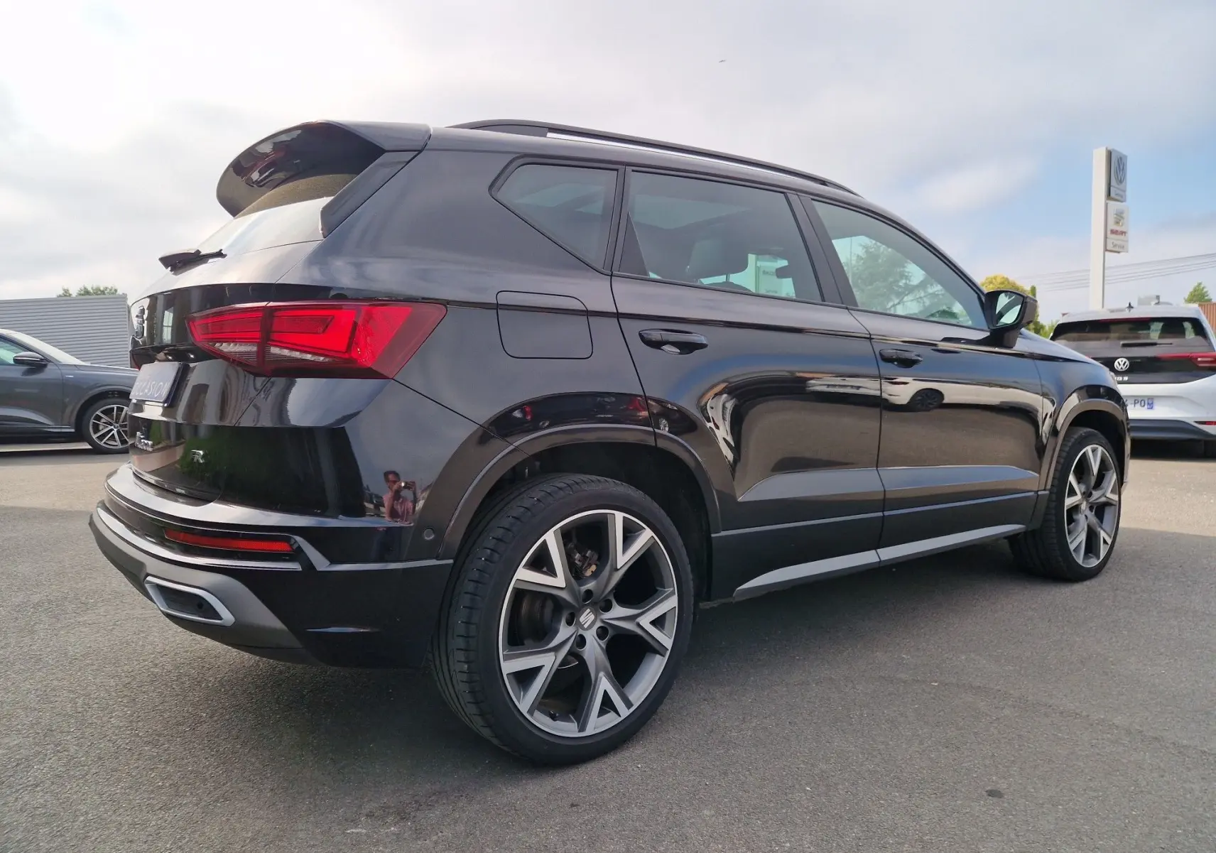 SEAT Ateca noire vue en 3/4 arrière droit, avec jantes alu 19'' et toit panoramique électrique visible.