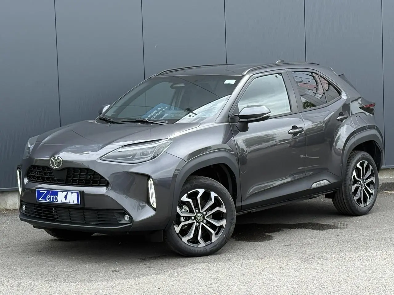 Toyota Yaris Cross gris Atlas vue 3/4 avant droit, avec jantes alliage noires et détails LED verticaux.