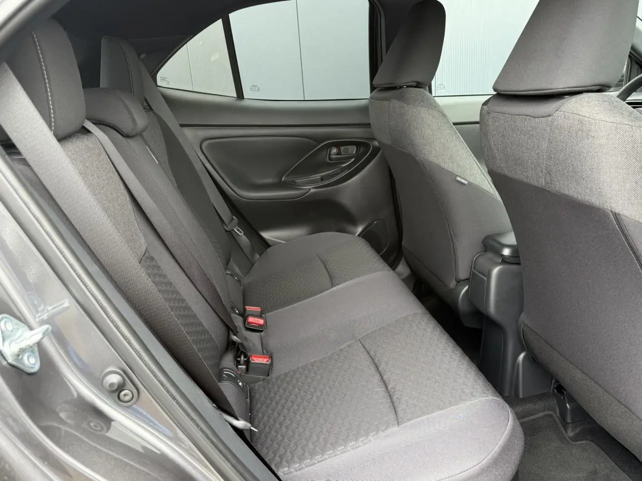 Vue côté gauche des sièges arrière gris foncé du Toyota Yaris Cross 1.5 Hybrid 2026 avec ceinture de sécurité visible.