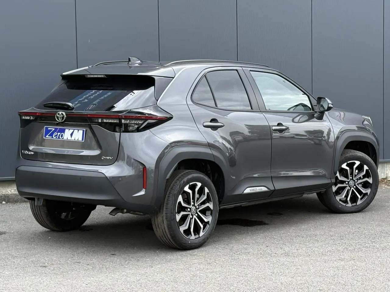 Vue 3/4 arrière droite d'une Toyota Yaris Cross 1.5 Hybrid gris Atlas avec jantes alliage et feux arrière LED.