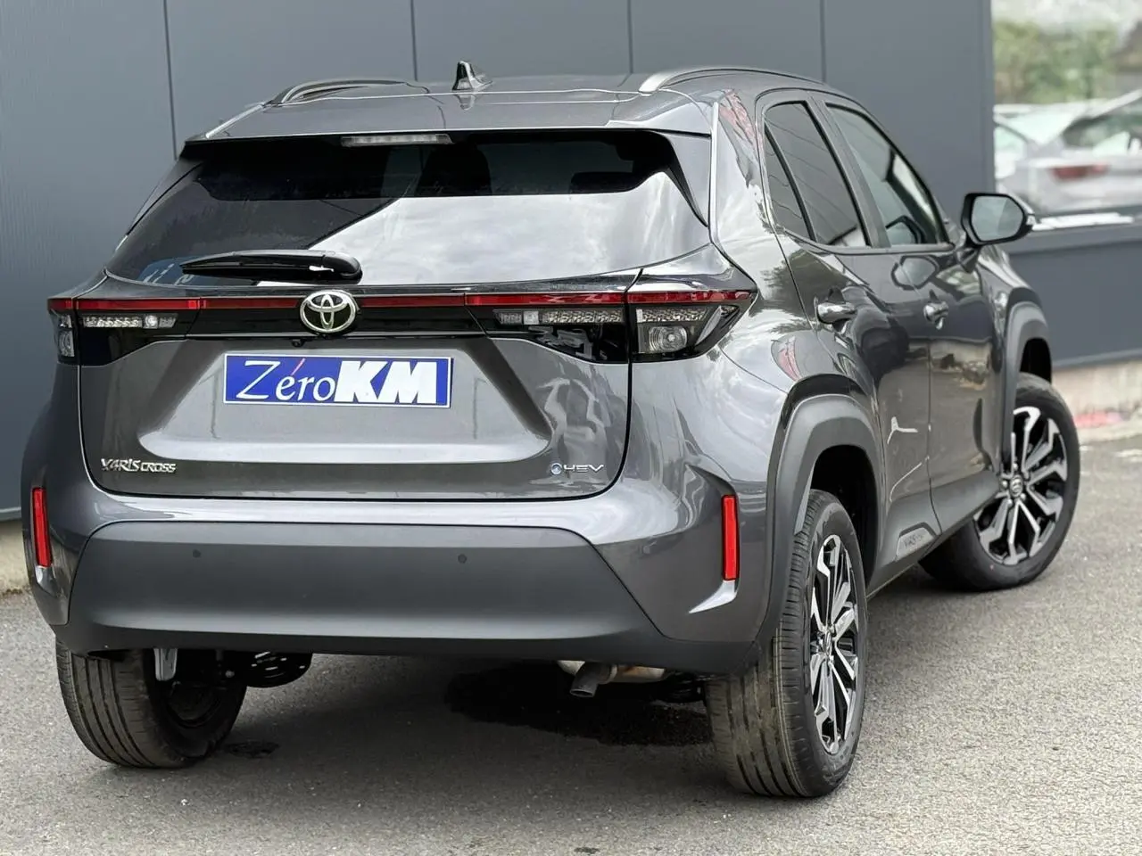 Vue 3/4 arrière droite d'une Toyota Yaris Cross 1.5 Hybrid 116 Design gris Atlas avec feux arrière LED et jantes alliage.