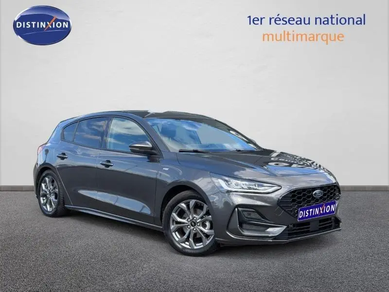 Ford Focus 2025 gris lunaire métallisé vue 3/4 avant avec calandre noire et jantes alu brillantes.