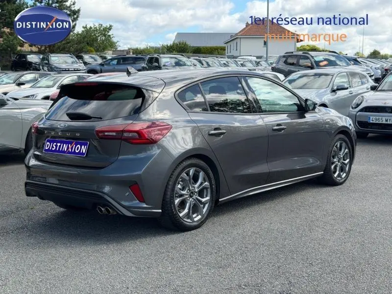 Ford Focus 1.5 EcoBlue 115ch ST-Line X gris lunaire métallisé vue 3/4 arrière droit avec jantes alu et double sortie d’échappement.