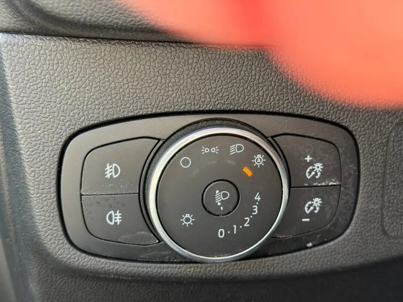 Gros plan sur la commande des phares de la Ford Focus 1.5 EcoBlue gris lunaire, avec réglage d'intensité lumineux activé.