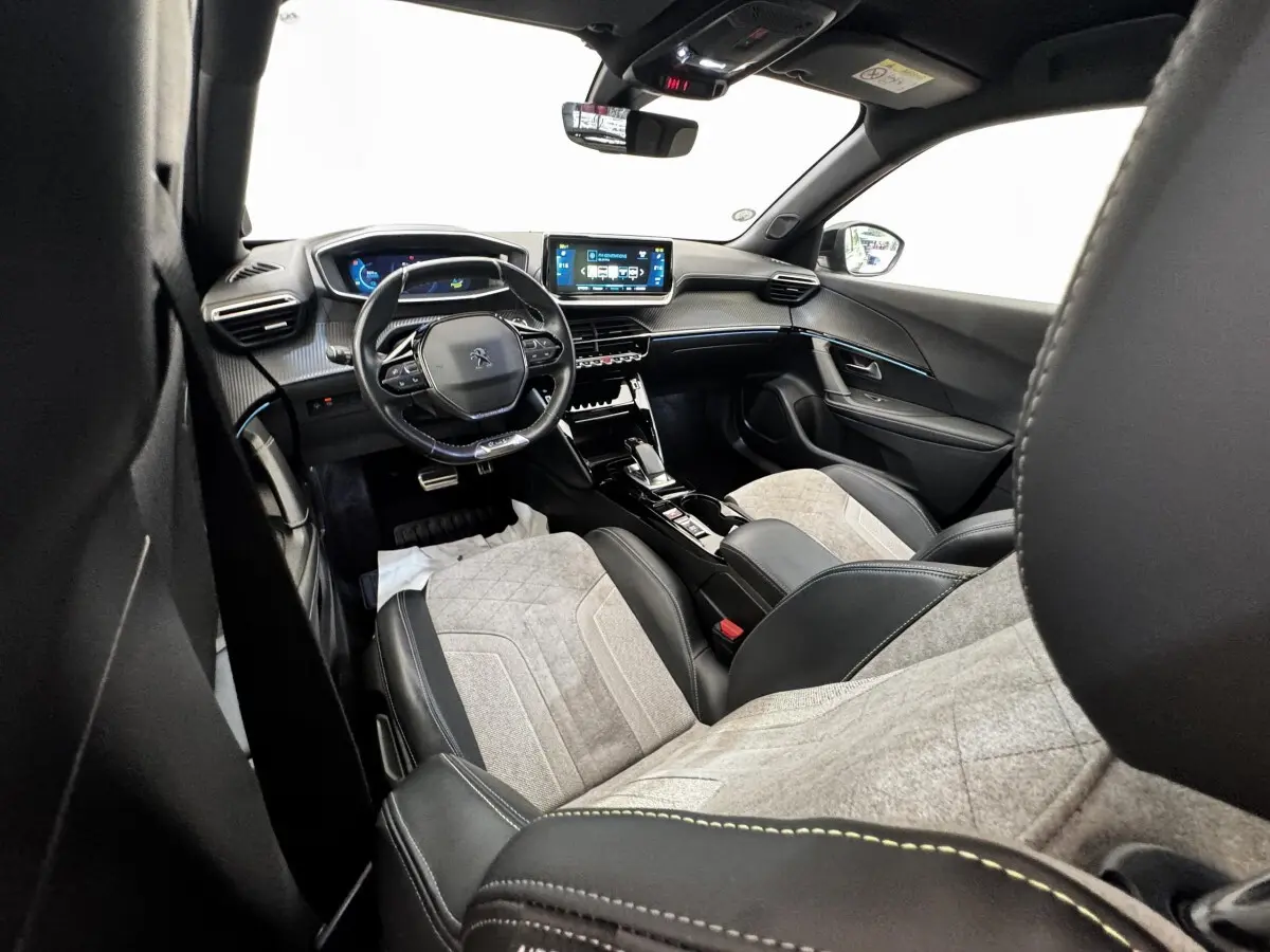 Intérieur de la Peugeot E-2008 GT Pack électrique 2021, vue avant droite, sièges tissu gris et cuir noir, tableau de bord digital.