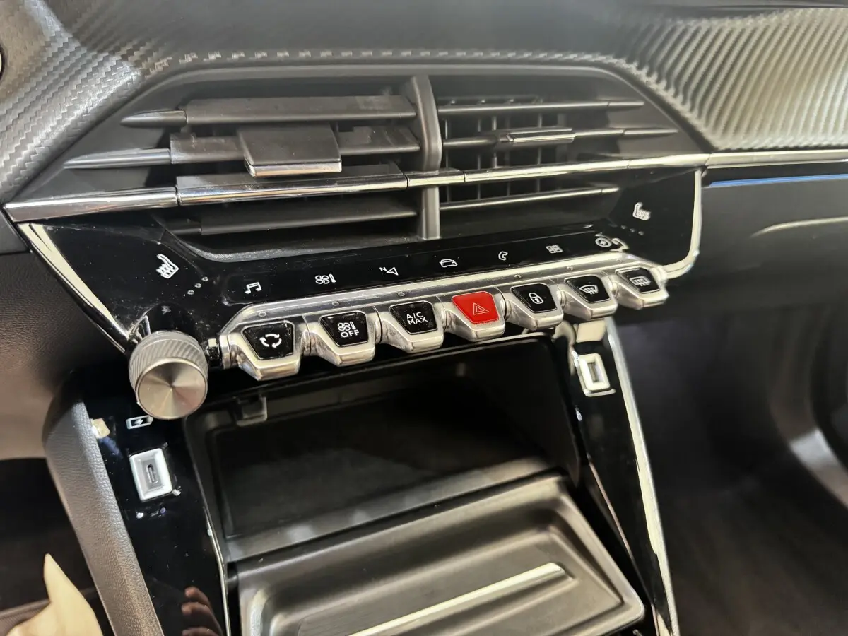 Gros plan sur la console centrale noire du Peugeot E-2008 électrique GT Pack 2021 avec boutons de commande et aérateurs.