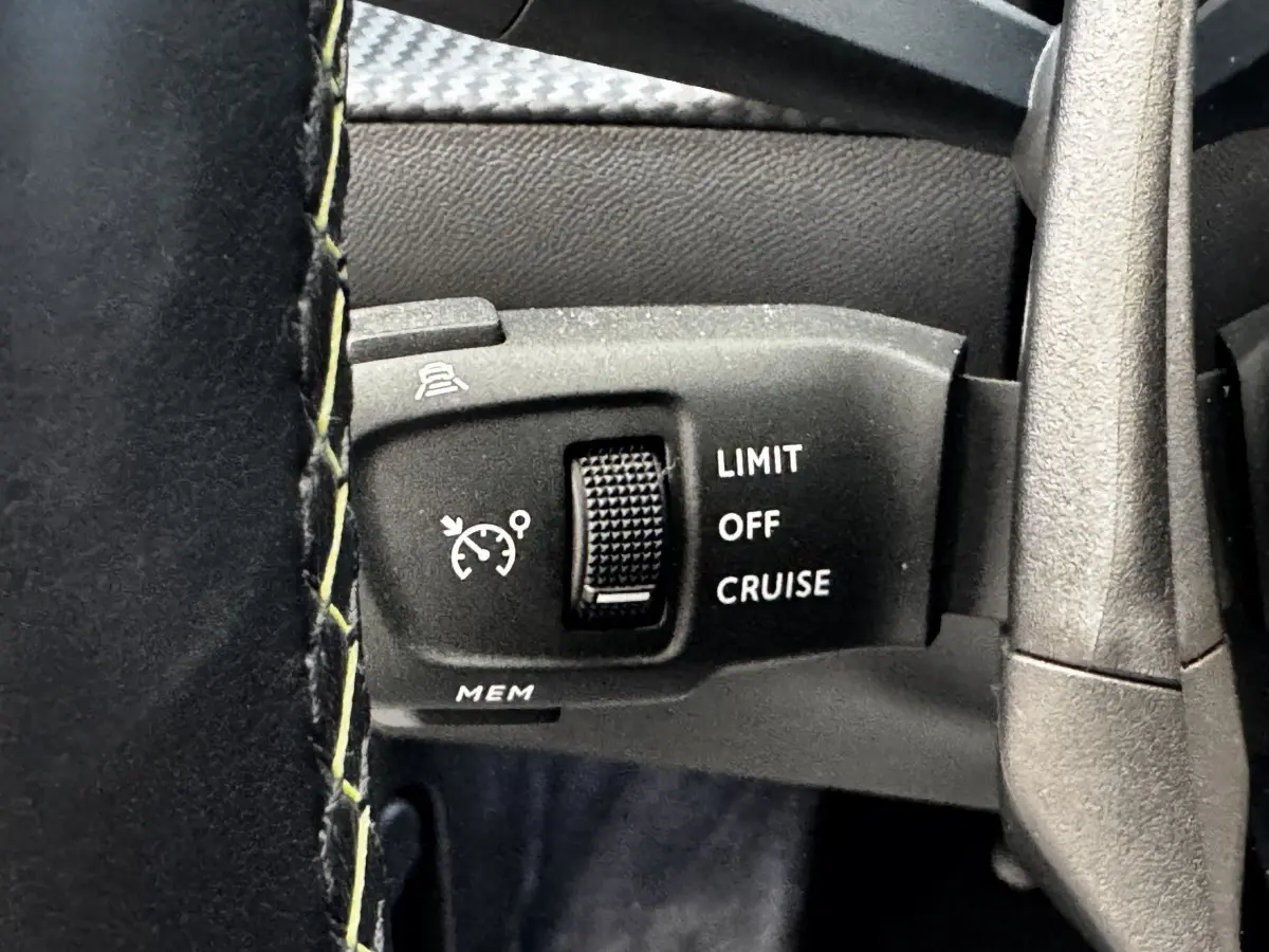 Gros plan sur la commande de régulateur de vitesse du volant cuir du Peugeot E-2008 GT Pack noir électrique.