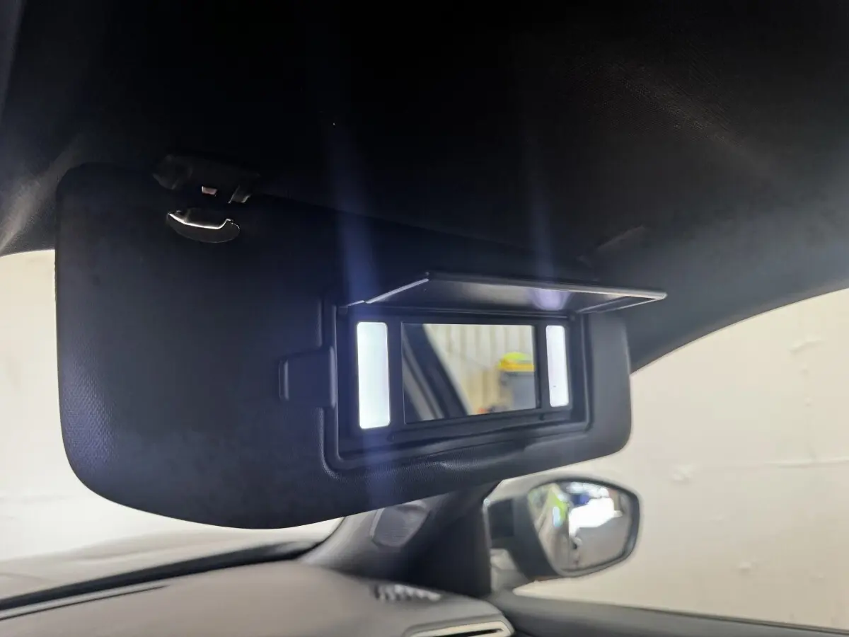 Détail du miroir de courtoisie éclairé sur pare-soleil intérieur côté gauche d’un Peugeot E-2008 noir électrique.