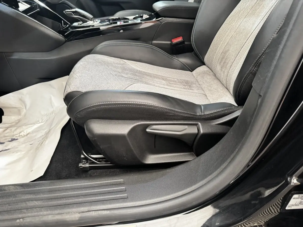 Vue rapprochée du siège avant droit gris et noir du Peugeot E-2008 électrique GT Pack noir, avec console centrale visible.