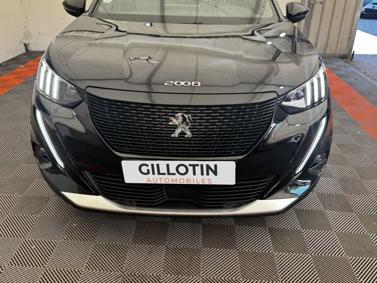 Vue frontale d’un Peugeot E-2008 électrique GT Pack noir, avec calandre noire et feux LED distinctifs allumés.