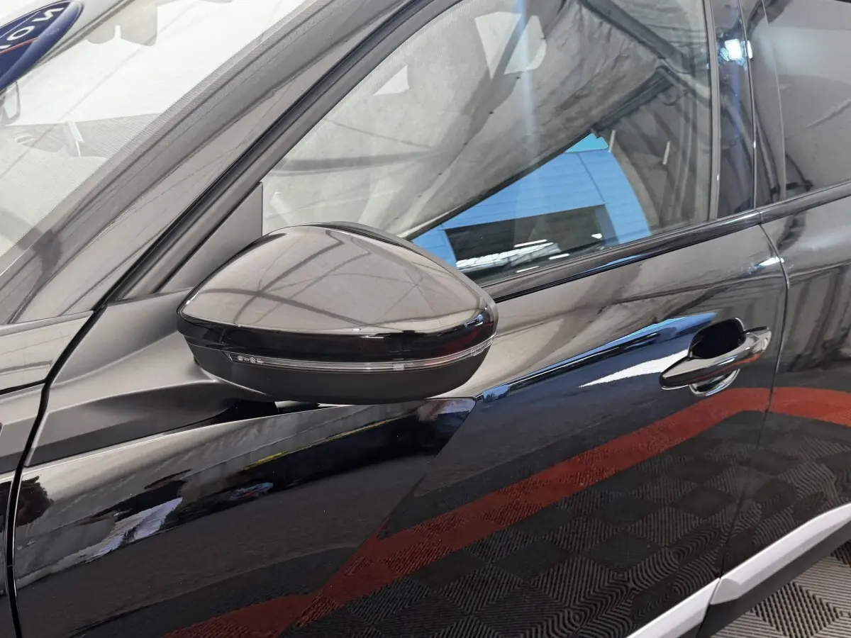 Gros plan sur le rétroviseur côté gauche et la porte noire brillante du Peugeot E-2008 électrique GT Pack.