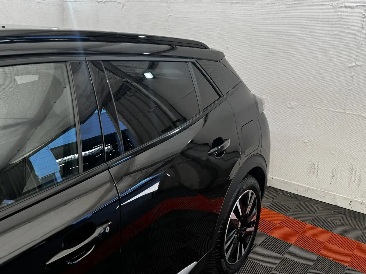 Vue latérale arrière droite du Peugeot E-2008 GT Pack électrique noir, avec jante alliage et vitres teintées.
