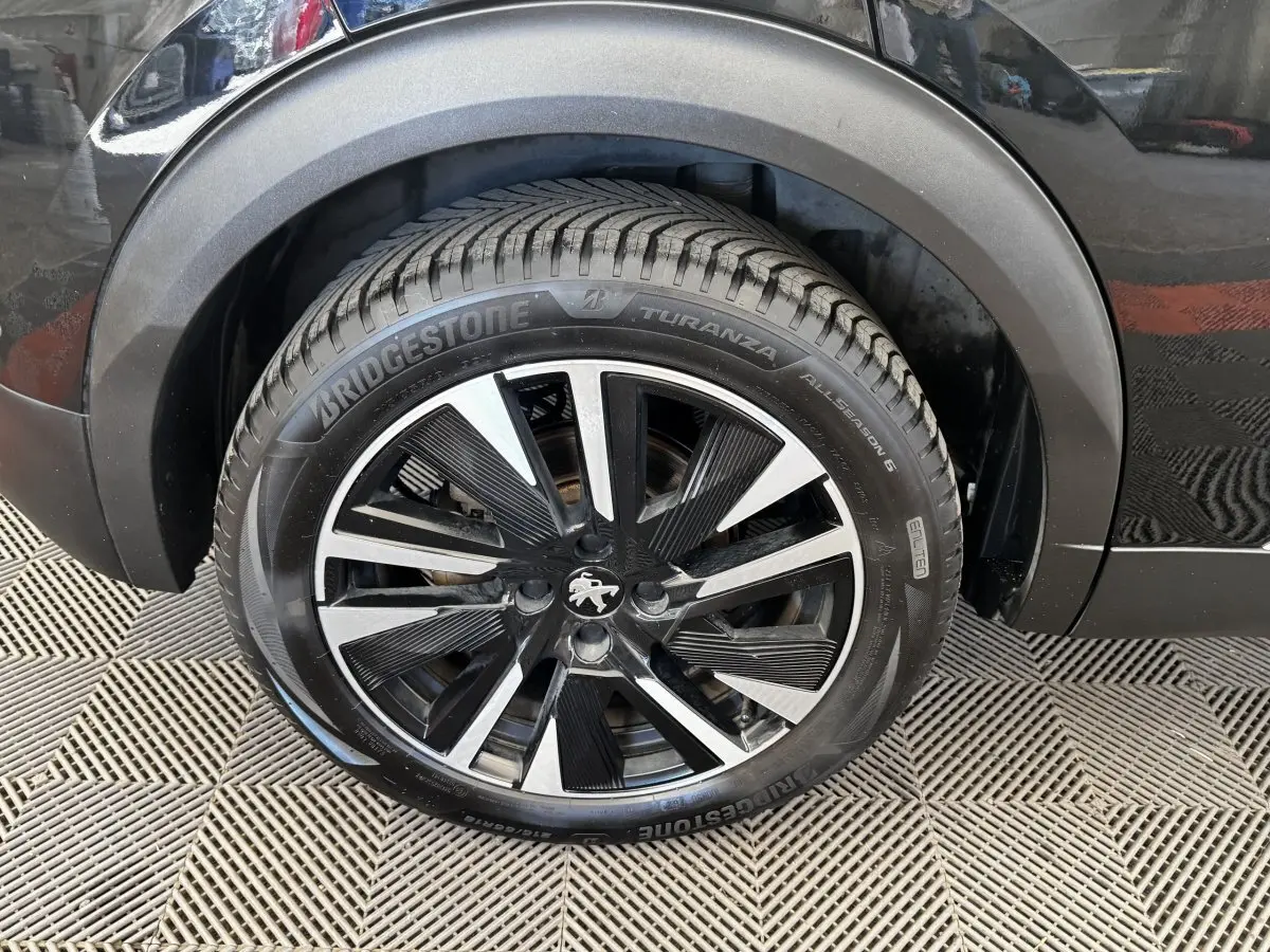 Gros plan sur la roue avant droite noire avec jante alliage bicolore du Peugeot E-2008 Electrique GT Pack 2021.