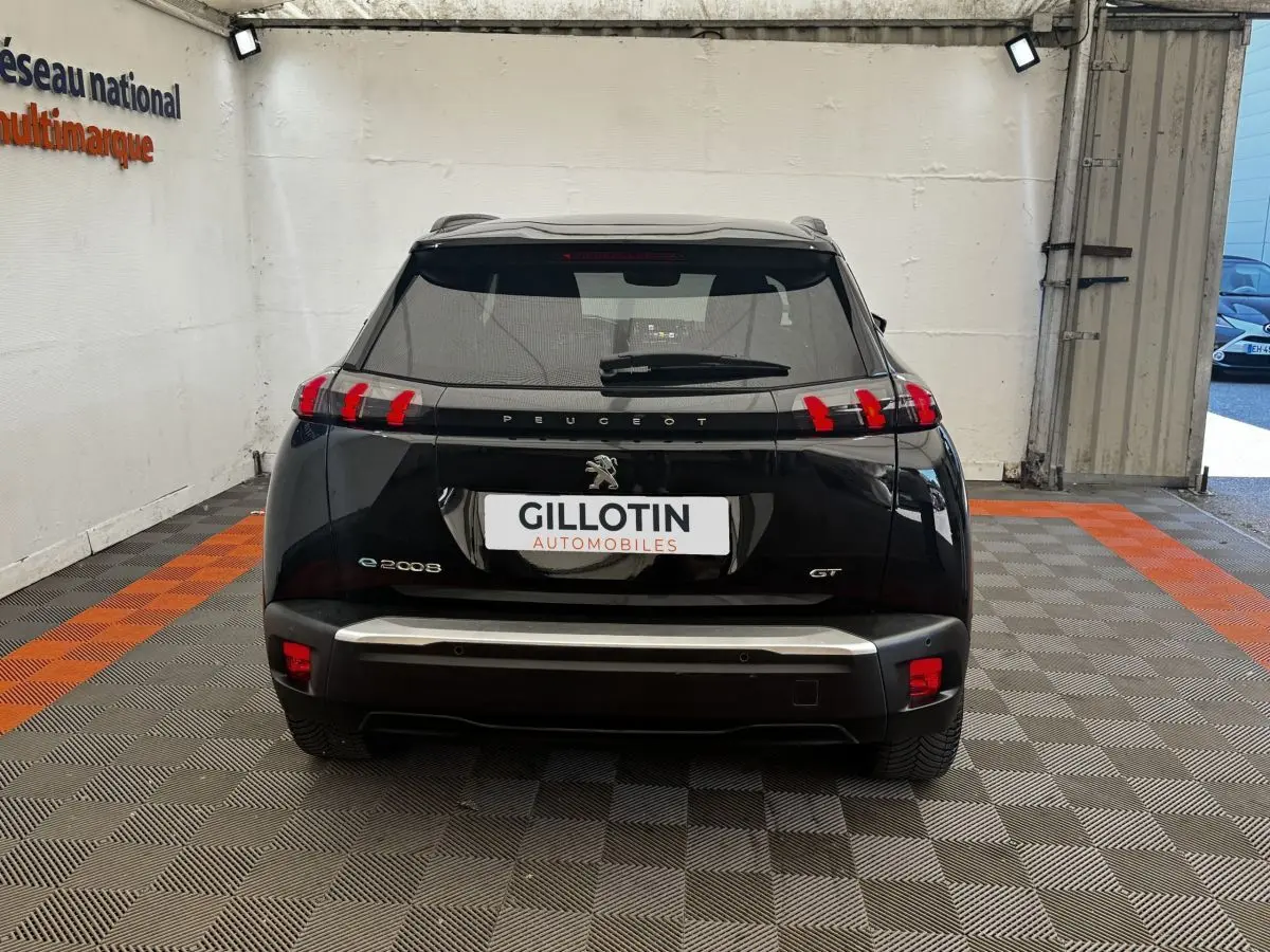 Vue arrière d'un Peugeot E-2008 GT Pack électrique noir, avec feux arrière distinctifs en forme de griffes rouges.
