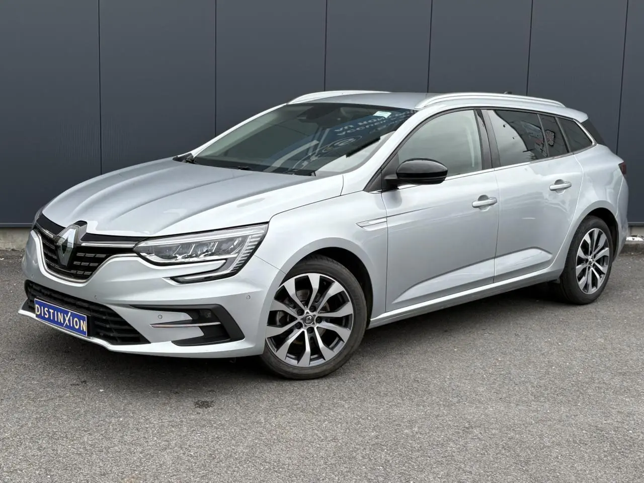 Renault Mégane Break gris Highland vue 3/4 avant droit avec jantes alliage et calandre noire distinctive.