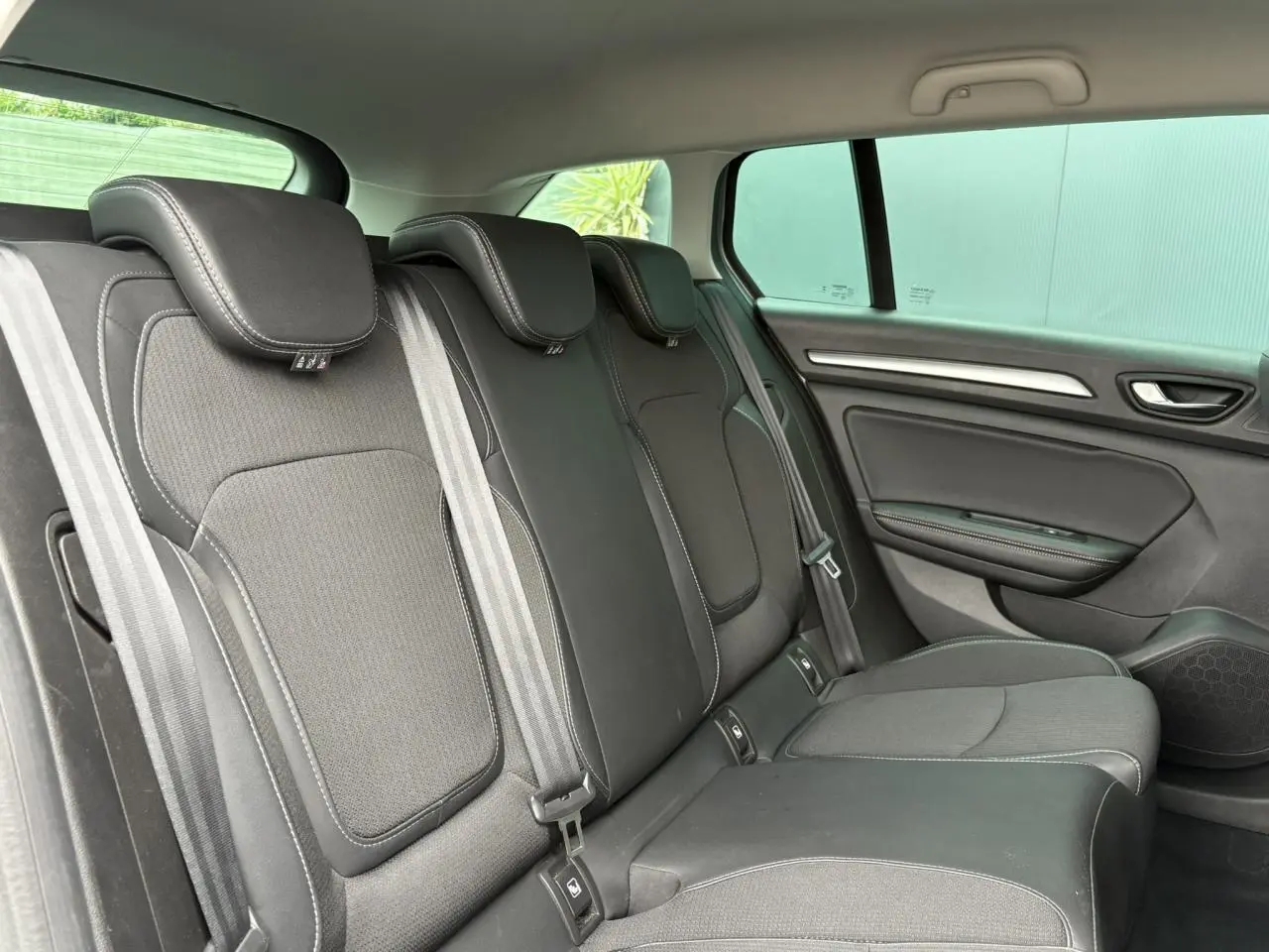 Vue latérale droite de la banquette arrière en tissu noir avec surpiqûres blanches dans une Renault Mégane Break 2024.