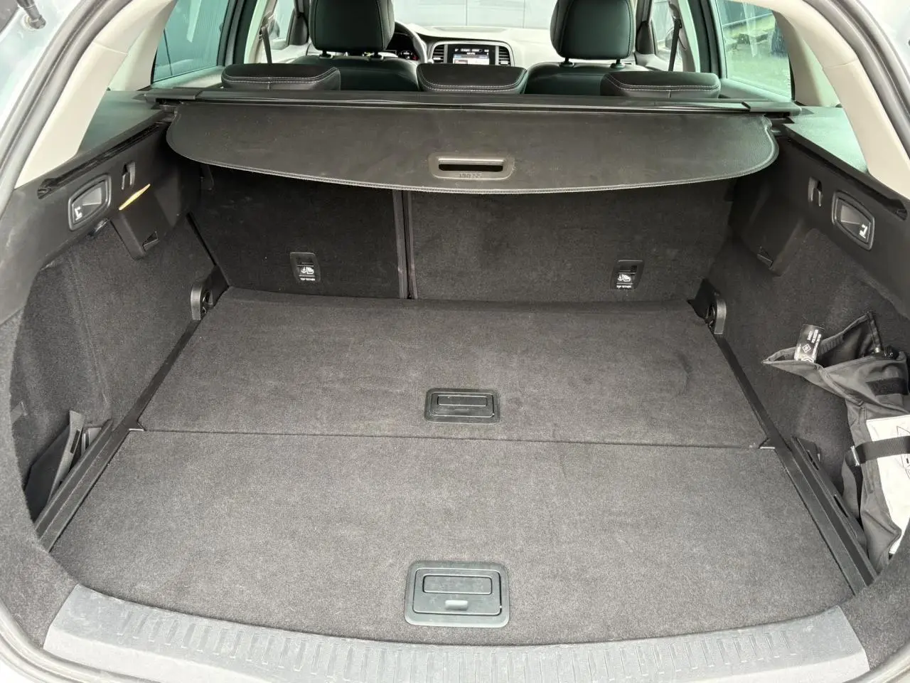 Coffre spacieux et vide de la Renault Mégane Break 2024 gris Highland, vue arrière ouverte avec cache-bagages déployé.