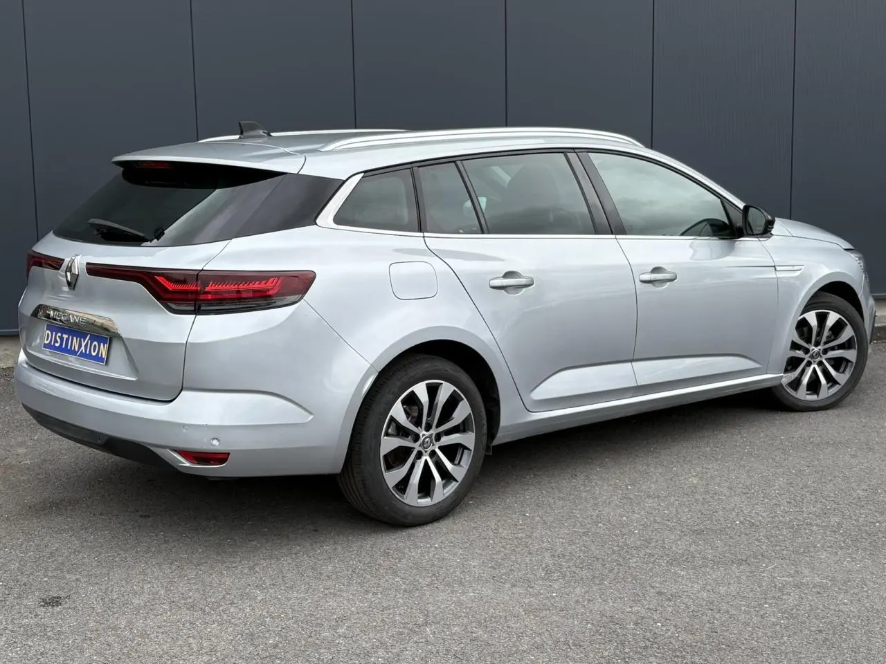 Renault Mégane Break gris Highland vue 3/4 arrière droit, avec feux arrière LED et jantes alliage 17 pouces.