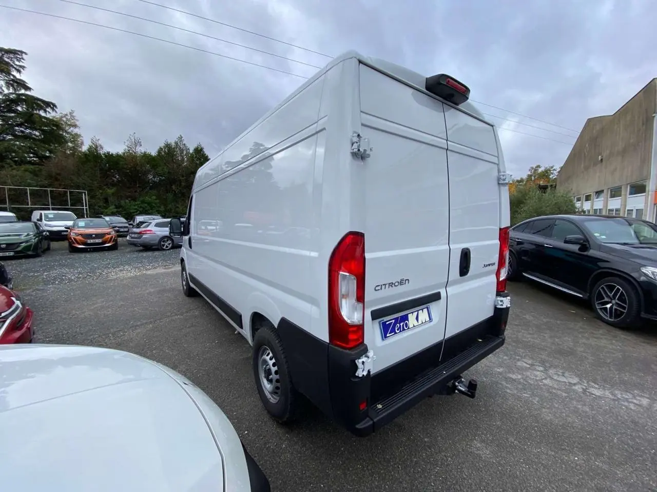 Vue 3/4 arrière droite d’un utilitaire Citroën Jumper blanc avec porte arrière ouverte et crochet d’attelage visible.