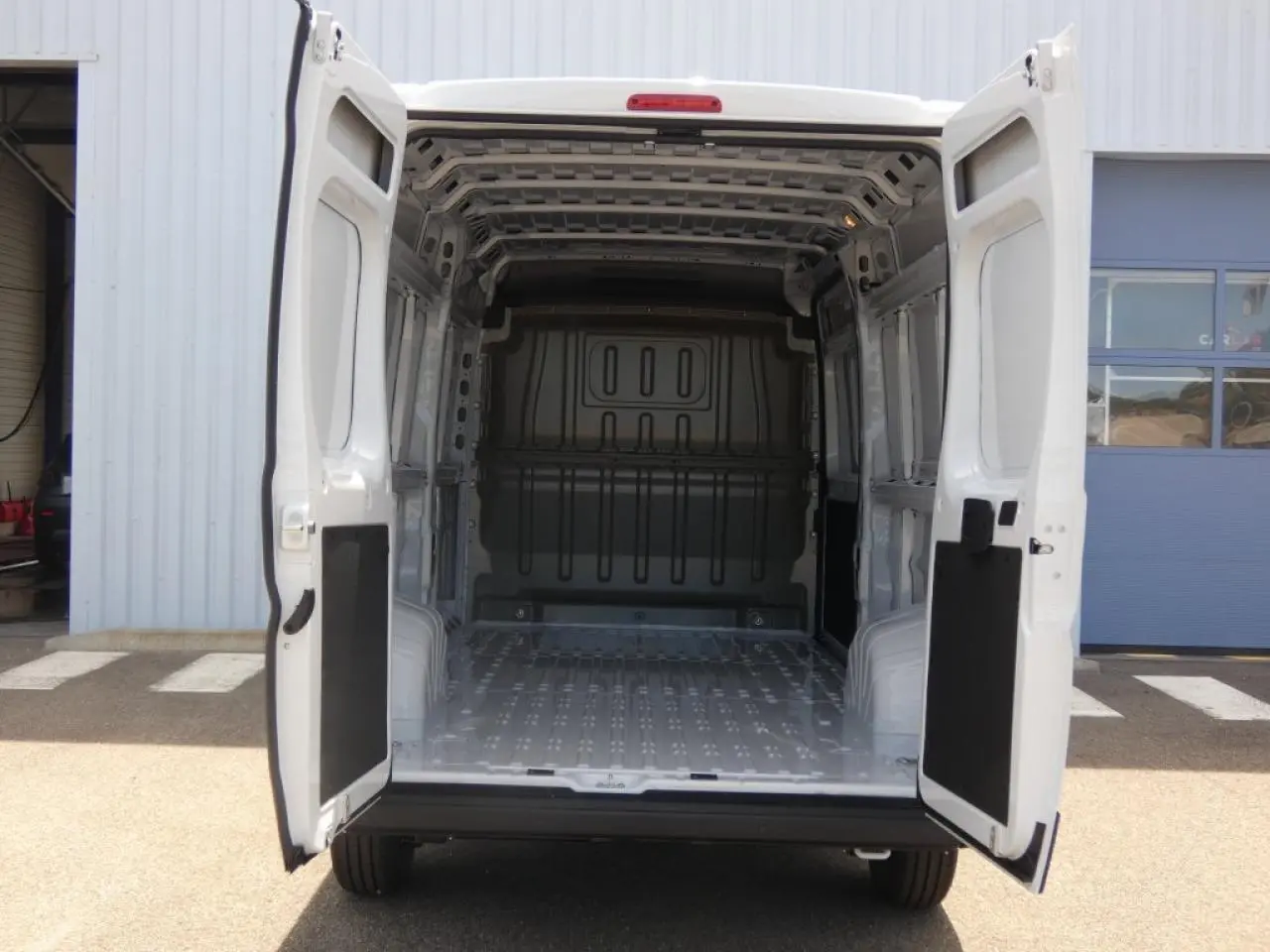 Vue arrière du Citroën Jumper blanc 2025 avec portes arrière ouvertes dévoilant l’espace de chargement vide.