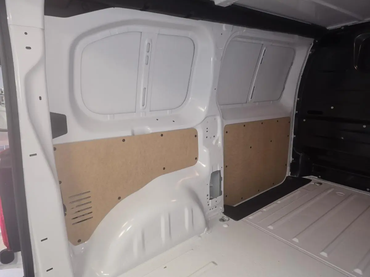 Intérieur de la zone de chargement du fourgon blanc Opel Vivaro M 2.0 BlueHDi 2025, vue latérale droite avec panneaux de protection bois.