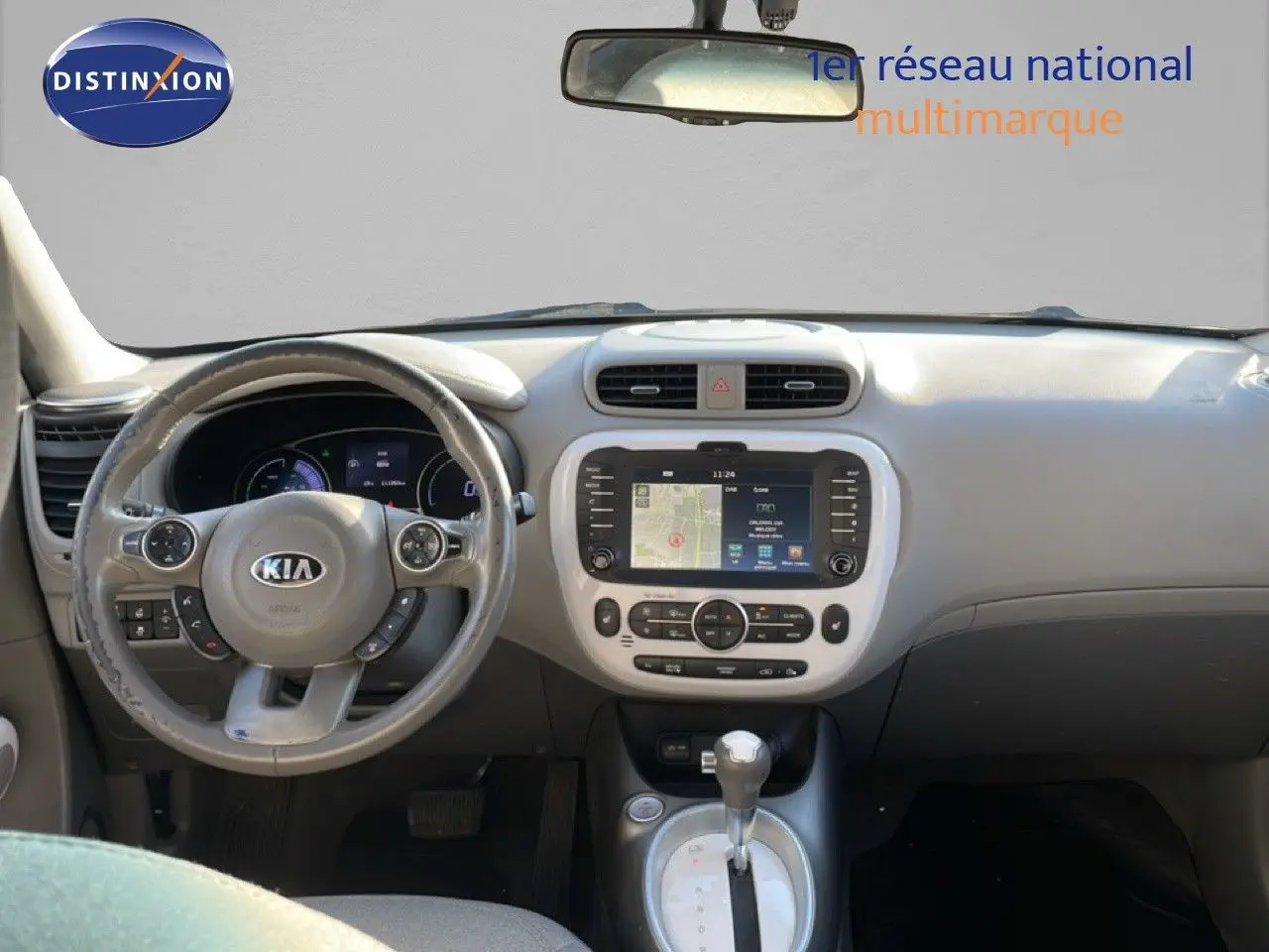 Vue intérieure frontale du tableau de bord et volant gris clair de la Kia Soul EV 2016 avec écran tactile central et levier de boîte automatique.