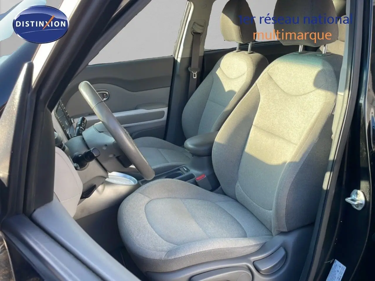 Vue intérieure côté conducteur du Kia Soul EV 2016 avec sièges tissu gris et volant multifonction.