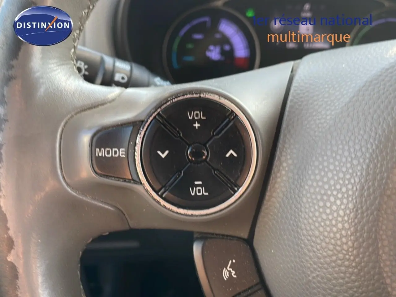 Gros plan sur les commandes de volume et mode au volant gris d'une KIA Soul EV électrique noir Shadow Metal avec toit rouge.
