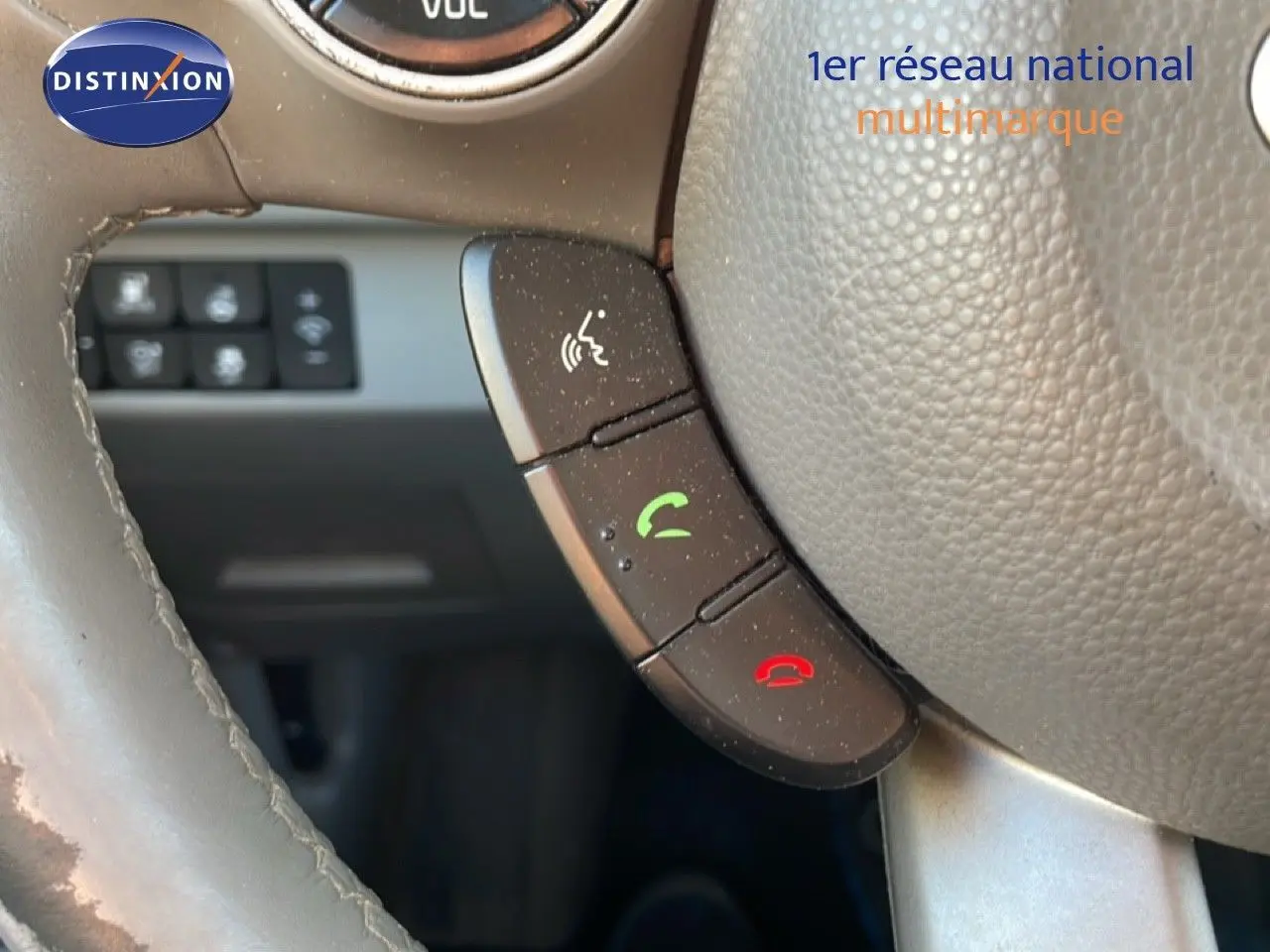 Gros plan sur les commandes téléphoniques au volant en cuir gris d'une KIA Soul EV 2016, intérieur visible en arrière-plan.