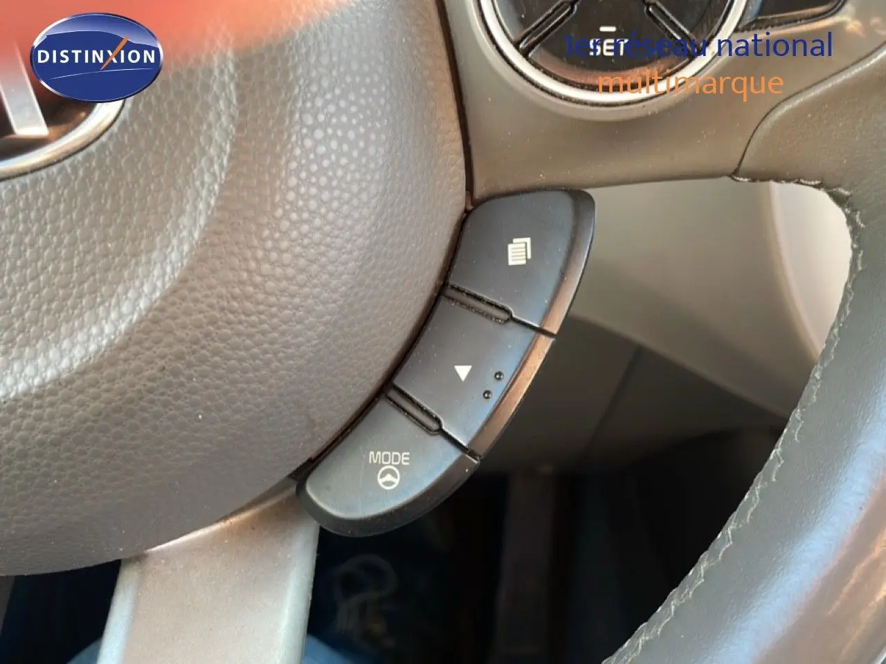 Gros plan sur les commandes au volant en cuir gris du Kia Soul EV électrique 2016, côté gauche.