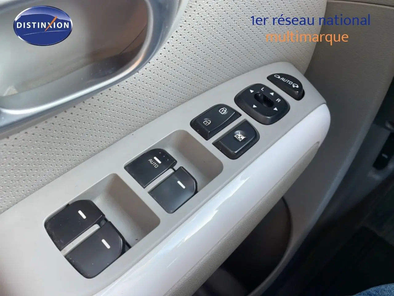 Gros plan sur les commandes des vitres et rétroviseurs côté conducteur d’une Kia Soul EV 2016 avec intérieur gris clair.