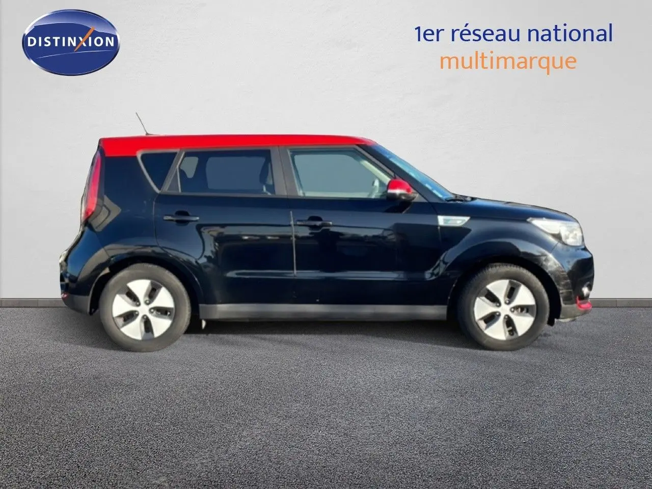 Profil côté gauche d’un KIA Soul EV 110ch noir Shadow Metal avec toit et rétroviseur rouge, en version électrique.