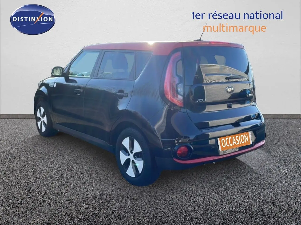 Vue 3/4 arrière droite d'une Kia Soul EV électrique noire Shadow Metal avec toit rouge et jantes blanches.