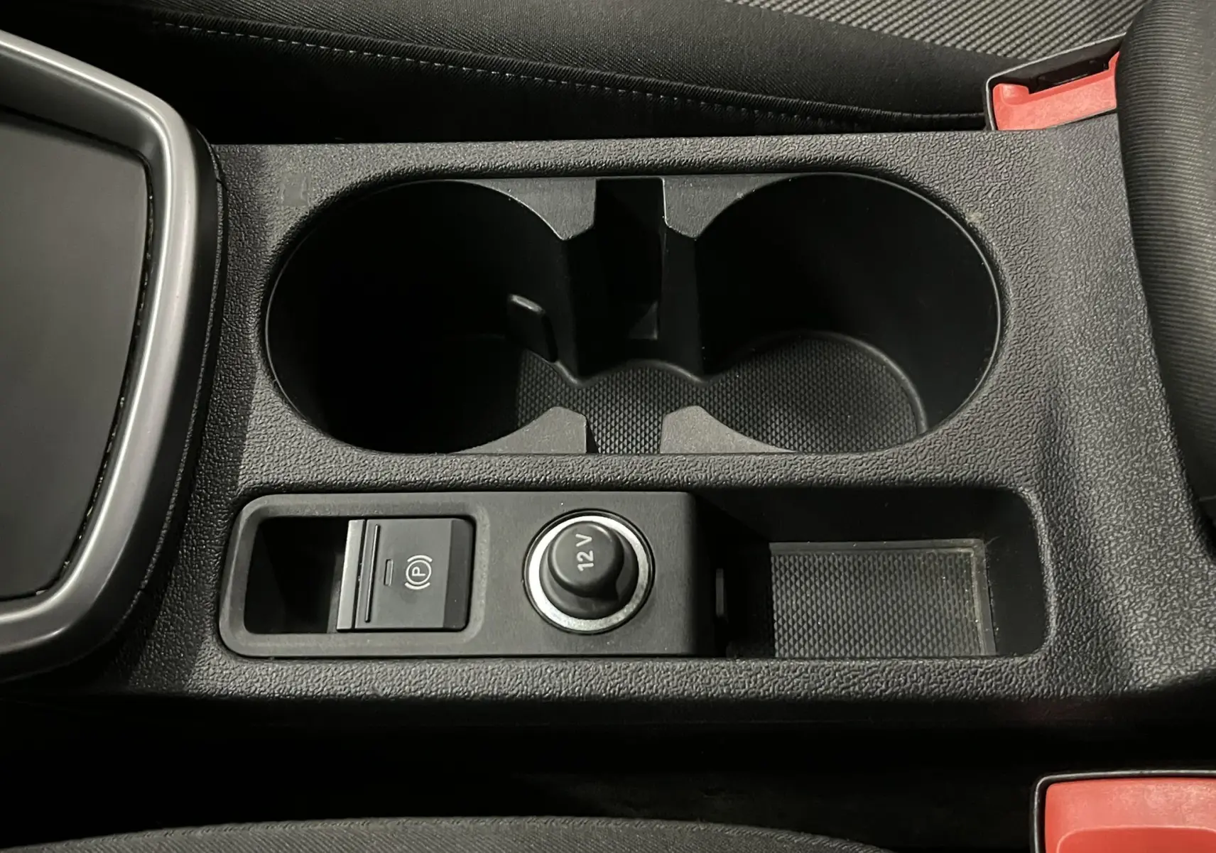 Gros plan sur la console centrale noire de l'Audi A3 Sportback 2021, avec porte-gobelets et prise 12V visible.
