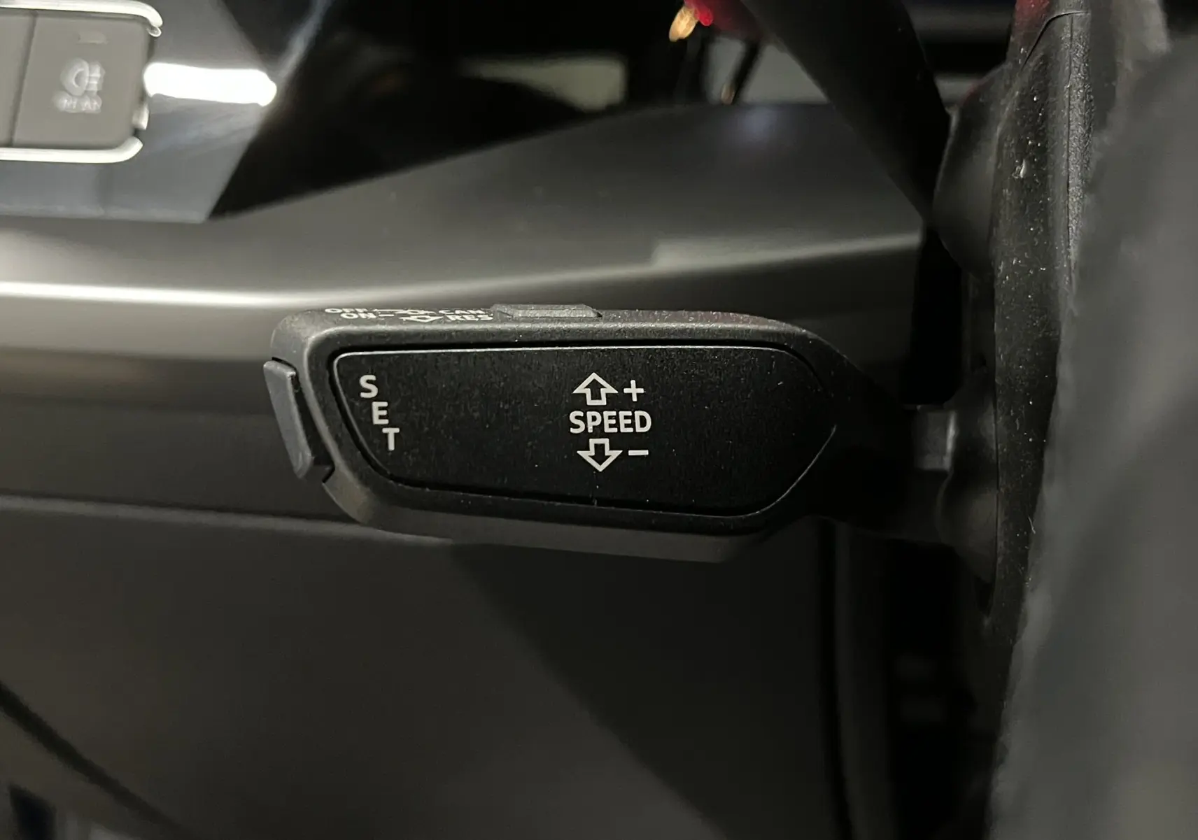 Gros plan sur la commande de régulateur de vitesse au volant d'une Audi A3 Sportback 30 TFSI bleu métallisé.