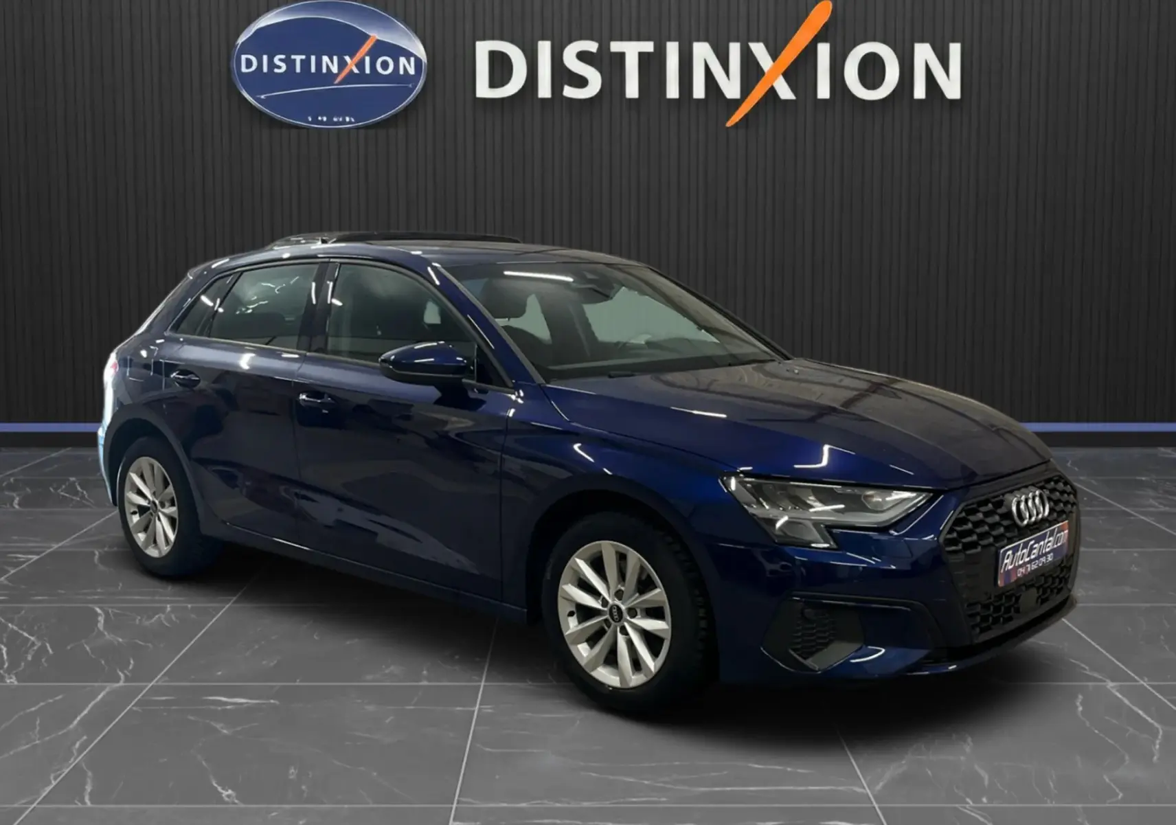 Audi A3 Sportback bleu métallisé vue 3/4 avant droit, avec calandre noire et jantes argentées en intérieur showroom.