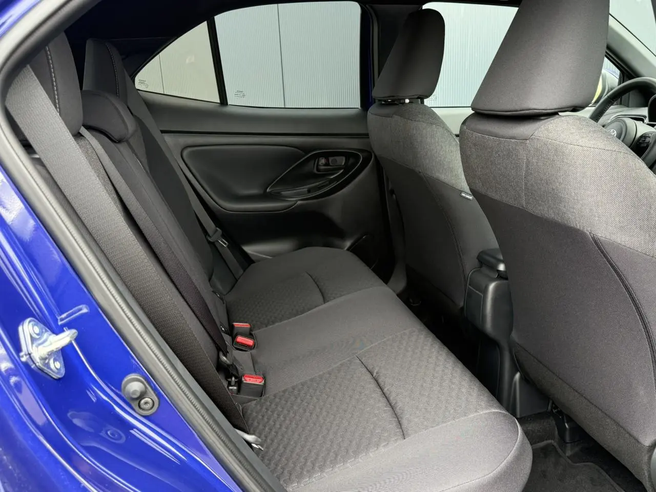 Vue intérieure côté gauche des sièges arrière noirs d'une Toyota Yaris Cross 1.5 Hybrid 116 Design bleu Genievre.