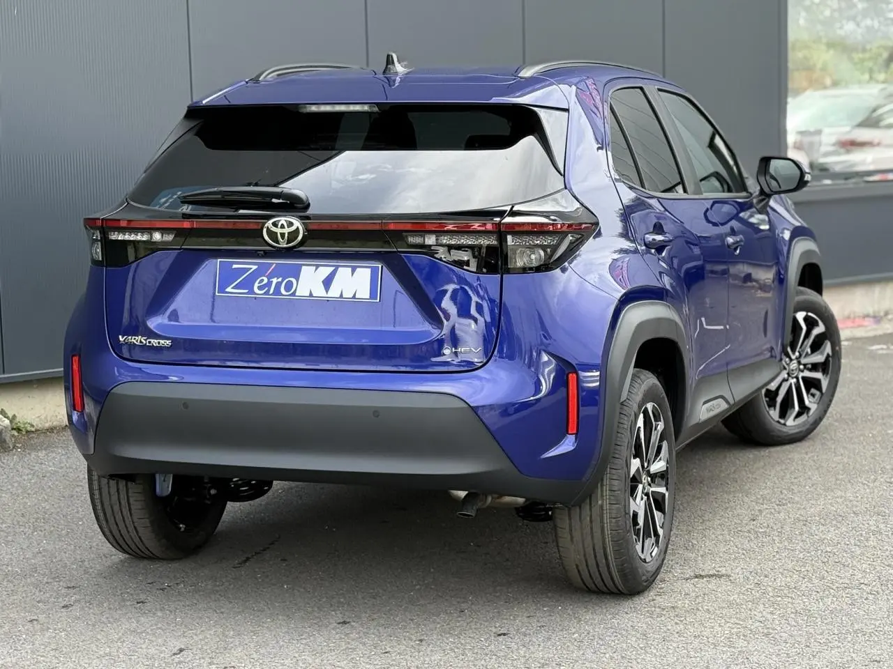 Vue 3/4 arrière droite d'une Toyota Yaris Cross 1.5 Hybrid bleu Genievre avec feux arrière LED et jantes alliage.