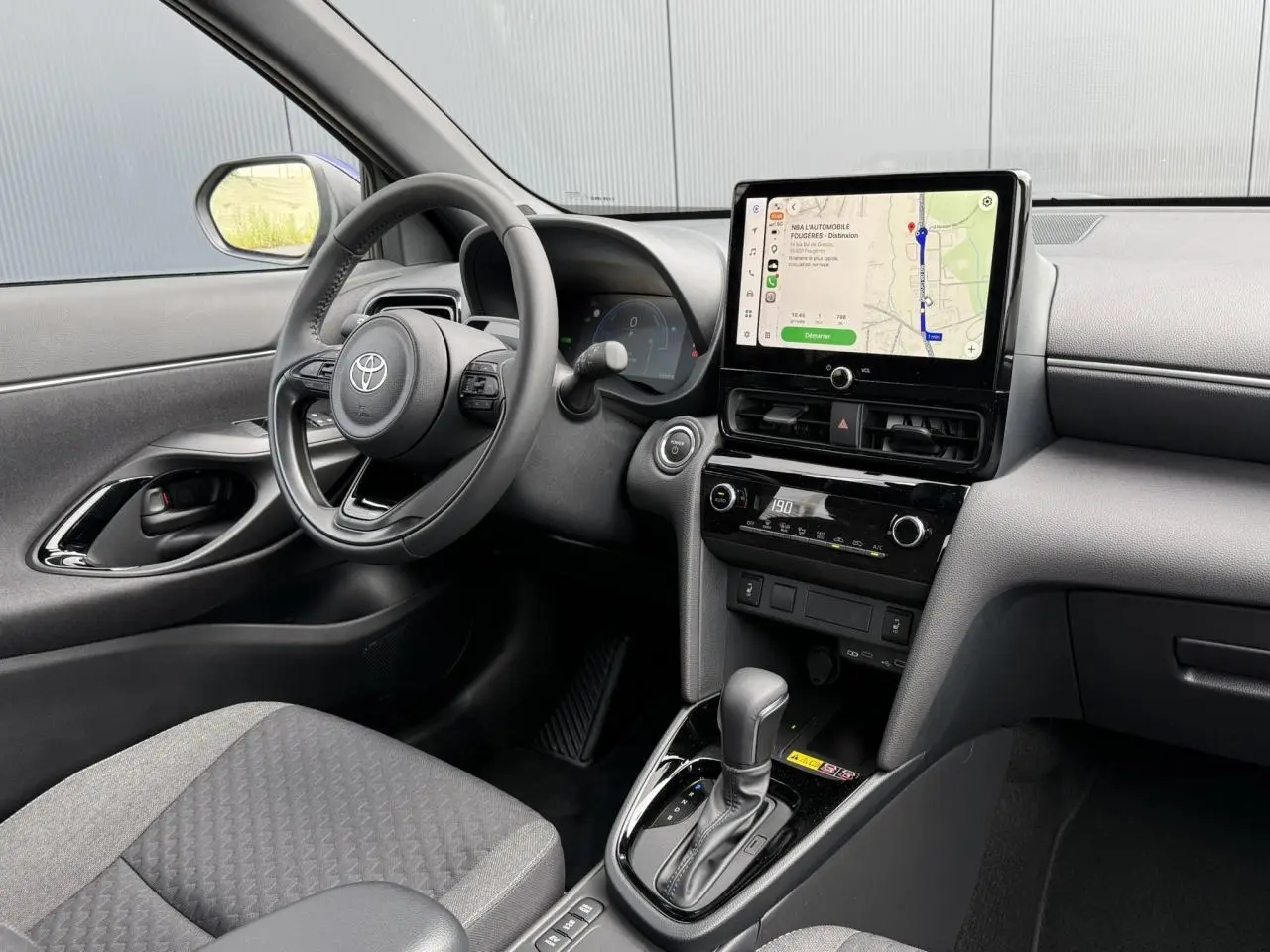 Intérieur de la Toyota Yaris Cross 1.5 Hybrid 116 Design 2026, vue côté conducteur sur le tableau de bord et écran tactile.