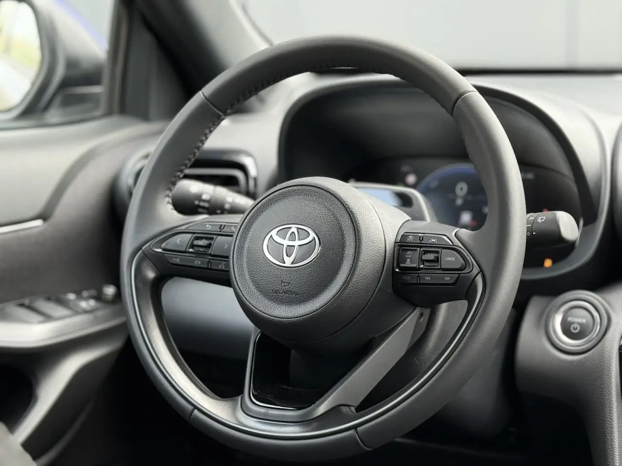 Vue rapprochée du volant cuir noir de la Toyota Yaris Cross 2026, avec commandes intégrées et bouton démarrage.