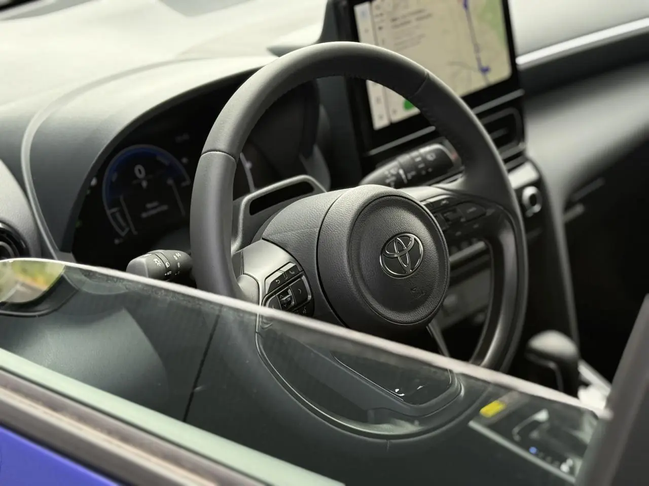 Vue intérieure côté conducteur du Toyota Yaris Cross 2026 bleu Genievre, avec volant cuir et écran tactile central.