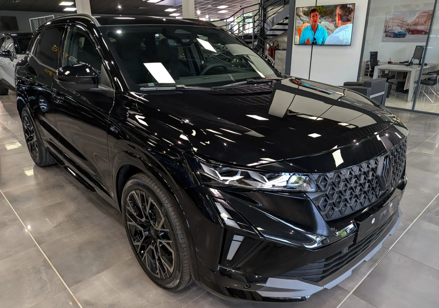 Renault Austral full hybrid noir en 3/4 avant droit, avec calandre texturée et jantes noires distinctives.