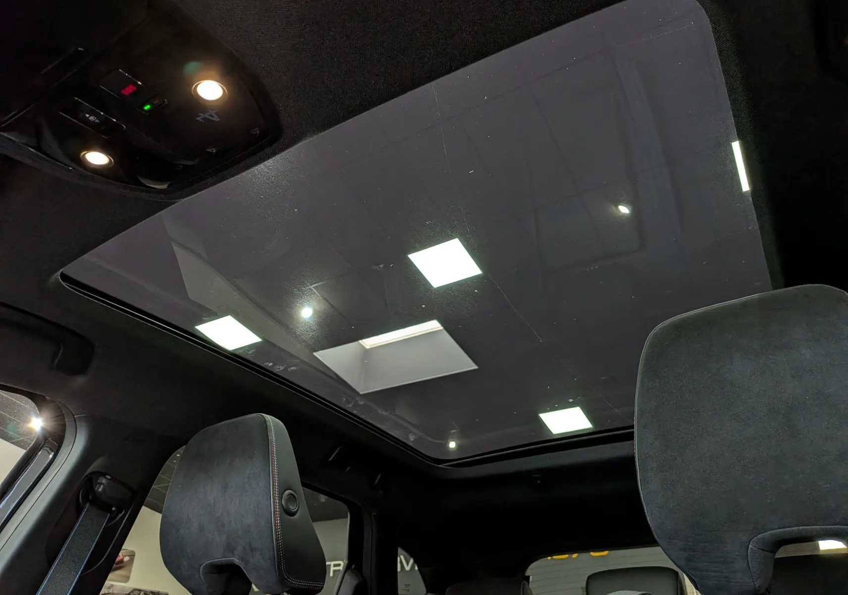 Vue intérieure du toit ouvrant panoramique du Renault Austral noir, avec sièges avant en tissu noir et éclairage intérieur.